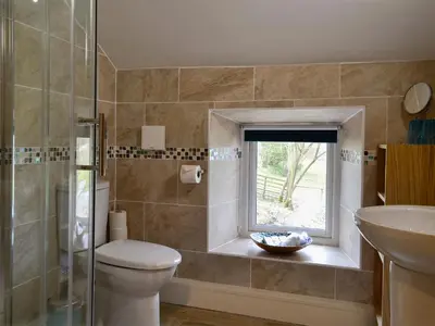 a bathroom with a toilet and a sink and a window at Farmhouse Cottage - Uk1285 in Westward