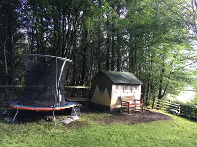 a small house and a trampoline in the grass at Lovely house next to Euchan River in Sanquhar