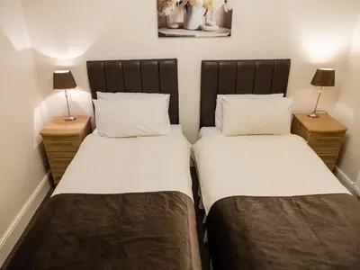 two beds in a small room with two lamps at Rosslyn in Douglas
