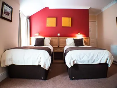 two beds in a room with a red wall at Rosslyn in Douglas