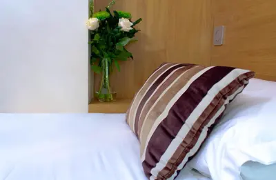 a vase of flowers sitting next to a bed with a pillow at Ellan Vannin Hotel in Douglas