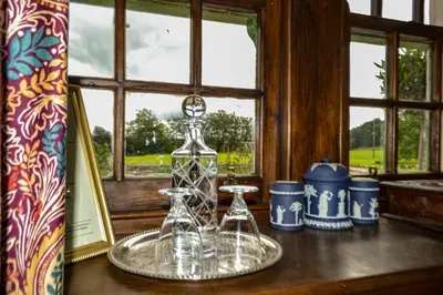 a table with a glass bottle and two glasses on it at The Lady Maxwell Room at Buittle Castle in Dalbeattie