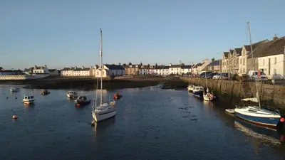 a group of boats are docked in a river at 4 Laigh Isle in Isle of Whithorn
