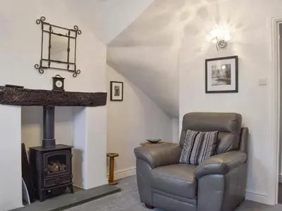 a living room with a chair and a stove at Bobbin Cottage in Keswick