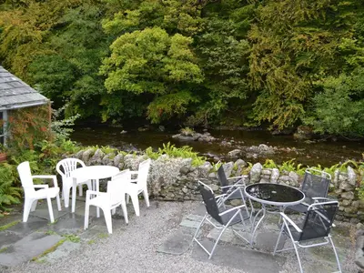 a group of chairs and tables next to a river at Bobbin Cottage in Keswick