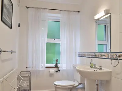 a bathroom with a toilet and a sink and a window at Bobbin Cottage in Keswick