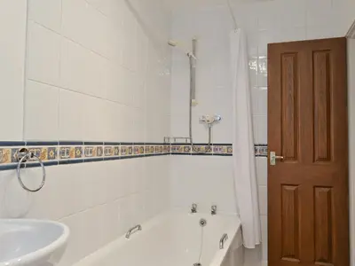 a white bathroom with a tub and a sink at Bobbin Cottage in Keswick