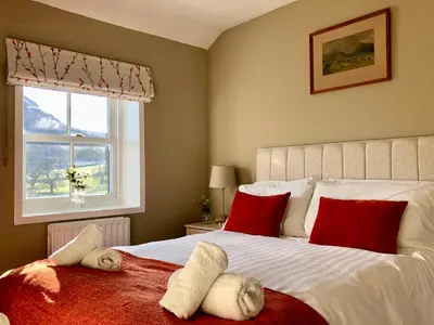 a bedroom with a bed with red pillows and a window at Kirkstile Inn in Loweswater