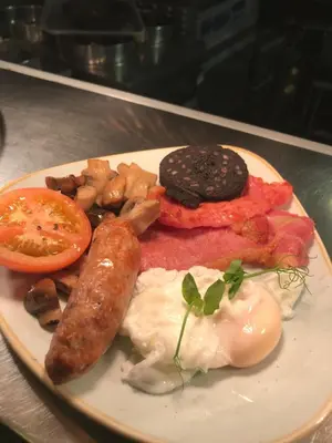 a plate of breakfast food with eggs sausage and tomatoes at Kirkstile Inn in Loweswater