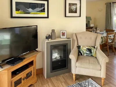 a living room with a television and a chair and a fireplace at Briargarth in Keswick