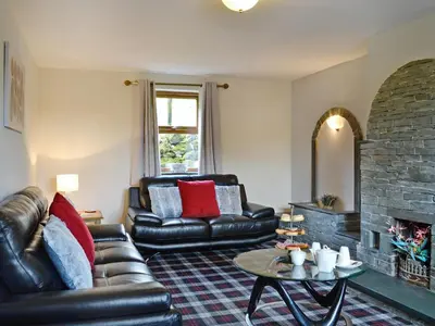 a living room with a leather couch and a fireplace at Grajo Cottage - Uk1284 in Threlkeld