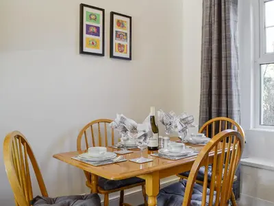 a wooden table with chairs and a bottle of wine at Apple Tree Cottage in Bassenthwaite