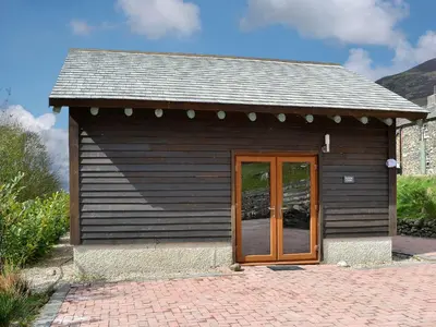 a small building with a wooden door on a patio at Darci's Lodge - Uk1297 in Threlkeld