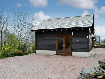 a small black building with a door on a brick patio at Darci's Lodge - Uk1297 in Threlkeld