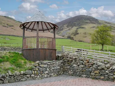 an umbrella over a stone wall with a fence at Darci's Lodge - Uk1297 in Threlkeld