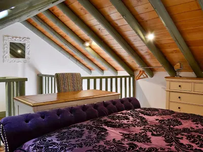a attic room with a purple bed and a desk at Darci's Lodge - Uk1297 in Threlkeld