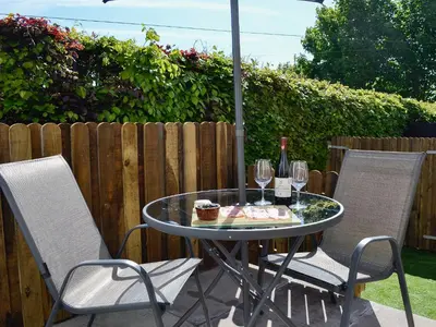 a table and two chairs with wine glasses and an umbrella at Little Cottage in Wigtown