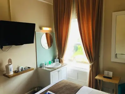 a room with a bed and a window with a sink at Cornerways Guest House in Carlisle
