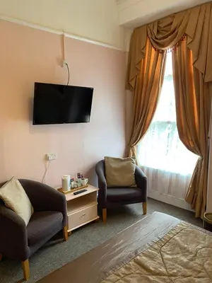 a living room with a tv and two chairs and a window at Cornerways Guest House in Carlisle