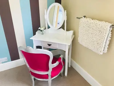 a bathroom with a pink chair and a mirror at Cornerways Guest House in Carlisle