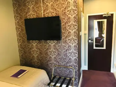 a bedroom with a bed and a flat screen tv on a wall at Cornerways Guest House in Carlisle