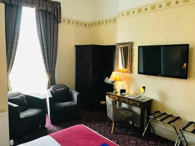 a hotel room with a bed and a desk and a television at Cornerways Guest House in Carlisle