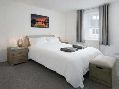 a bedroom with a large white bed and a window at Callander's High Street in Gatehouse of Fleet