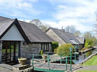 a house with a bridge next to a river at Waterwheel in Dalbeattie