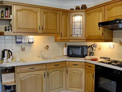 a kitchen with wooden cabinets and a sink and a microwave at Waterwheel in Dalbeattie