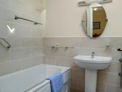 a bathroom with a tub and a sink and a mirror at Waterwheel in Dalbeattie