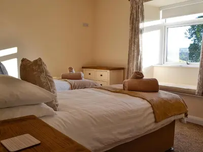 two beds in a room with a window at Liftingstane Dairy Cottage in Closeburn