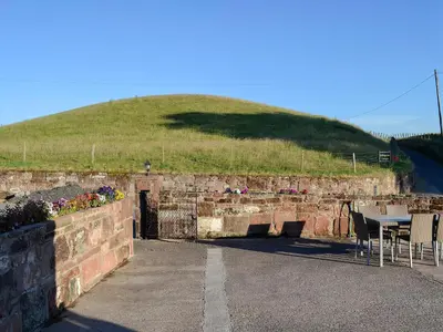 a stone wall with a table and a grassy hill at Liftingstane Dairy Cottage in Closeburn