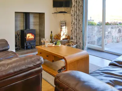 a living room with a table and a fireplace at Liftingstane Dairy Cottage in Closeburn