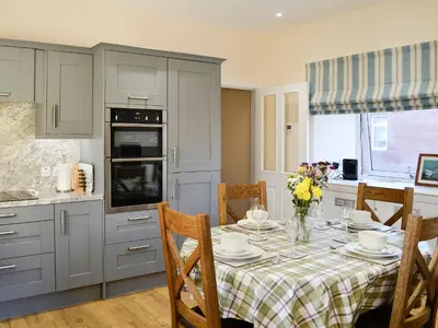 a kitchen with a table with plates and flowers on it at Liftingstane Dairy Cottage in Closeburn