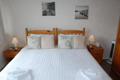 a bedroom with a large white bed with two lamps at Beckside Guest House Keswick in Keswick