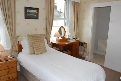 a bedroom with a bed and a desk and a mirror at Beckside Guest House Keswick in Keswick