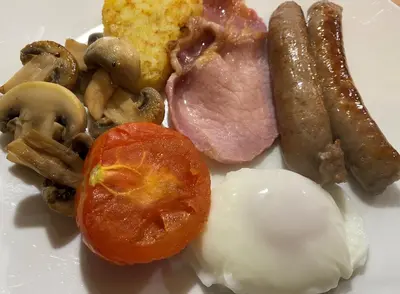 a plate of food with meat mushrooms and a tomato at Goodwin House in Keswick