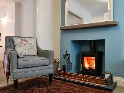 a living room with a chair and a fireplace at Applegarth in Cockermouth