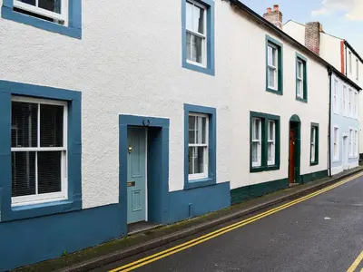 a row of white houses with blue doors on a street at Applegarth in Cockermouth