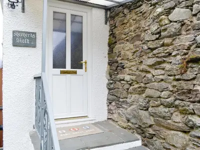 a white door on a stone building with a stone wall at Shepherds Bield - Uk1349 in Threlkeld