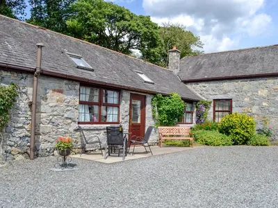 a stone house with a patio and chairs in front of it at Low Cordorcan - Uk5891 in Bargrennan