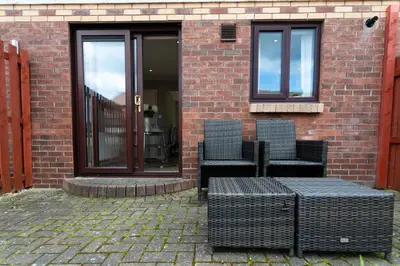 two chairs and a table in front of a brick building at The Huntington - Donnini Apartments in Ayr