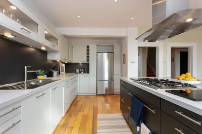 a large kitchen with white cabinets and black appliances at Sea Breeze - Donnini Apartments in Ayr