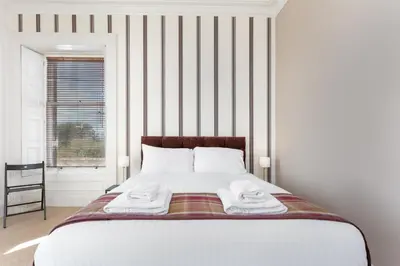 a bedroom with a large bed with towels on it at Sea Breeze - Donnini Apartments in Ayr
