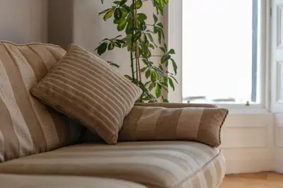 a couch with a pillow on it in a living room at Sea Breeze - Donnini Apartments in Ayr