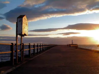 a pier stretches out into the ocean at sunset at Sea Breeze - Donnini Apartments in Ayr