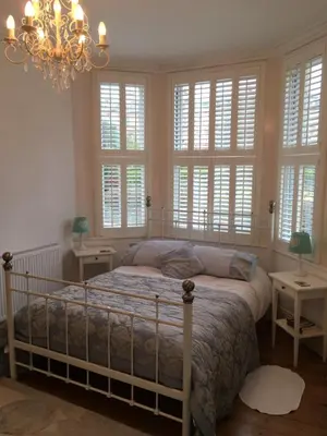 a bedroom with a bed with windows and a chandelier at Raymonds in Douglas