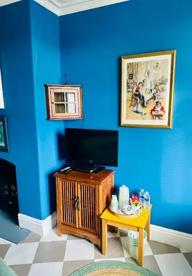 a room with a blue wall with a television on a table at Fitz House in Keswick