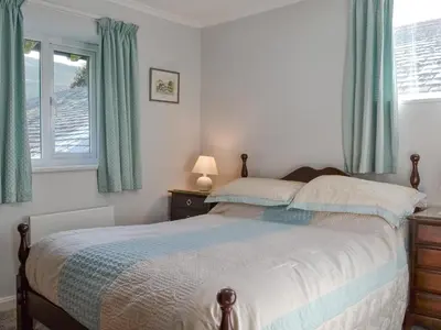 a bedroom with a bed with blue curtains and a window at Jose's At The Grange in Mockerkin
