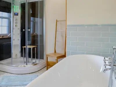 a bathroom with a bath tub and a shower at Holmegarth in Plumbland